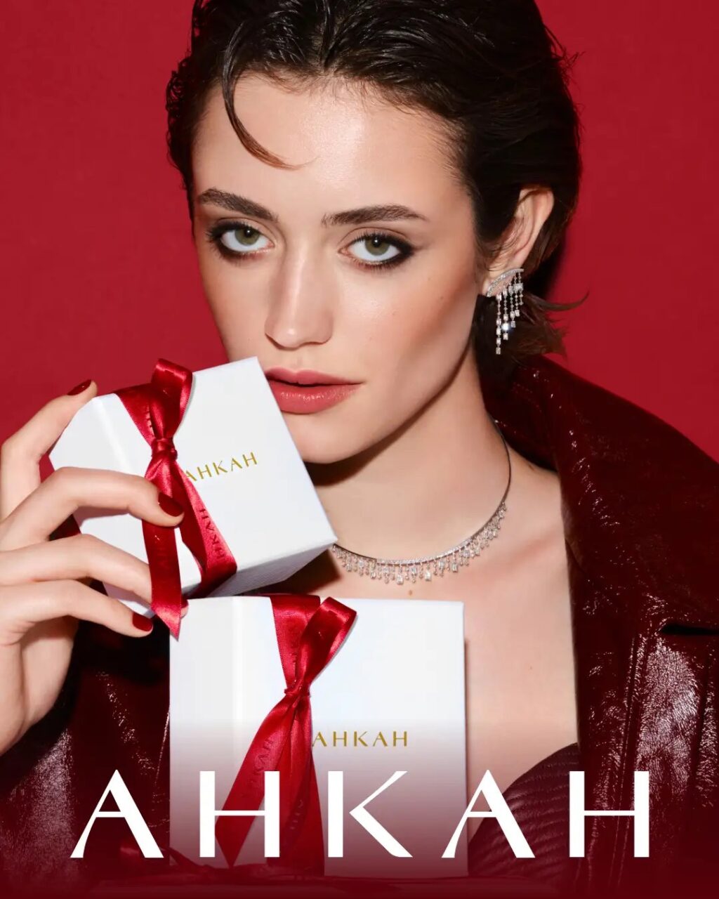 AHKAHのホリデージュエリーを着け、赤いリボンのギフトボックスを持つモデル